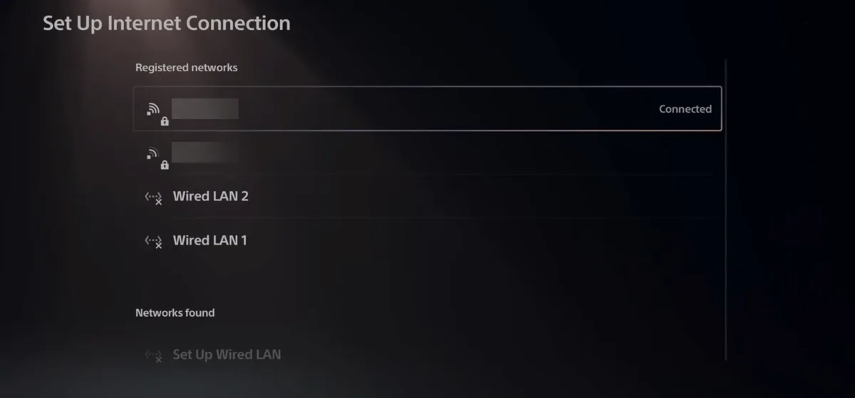 The PS5 Set Up Internet Connection screen. Under Registered networks the connected Wi-Fi network is highlighted and marked Connected, with a second Wi-Fi network, Wired LAN 2 and Wired LAN 1 below it. The Wi-Fi network names are blurred out.
